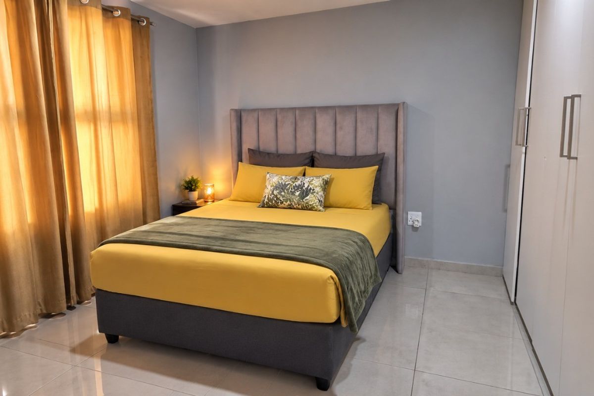 A well-maintained bedroom featuring neutral wall tones, large format floor tiles, and integrated built-in cupboards.