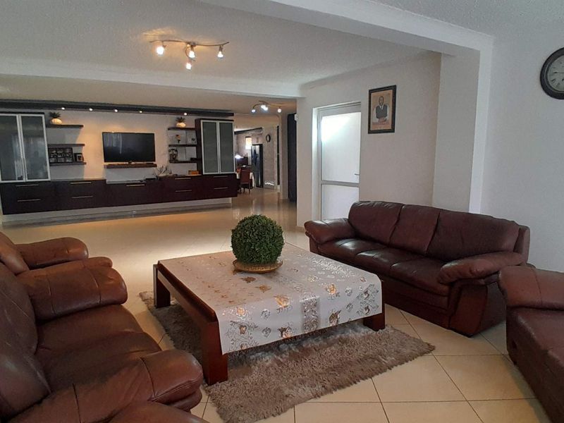 Spacious open-plan living area featuring tiled flooring, recessed lighting, and extensive built-in cabinetry for storage and media display.