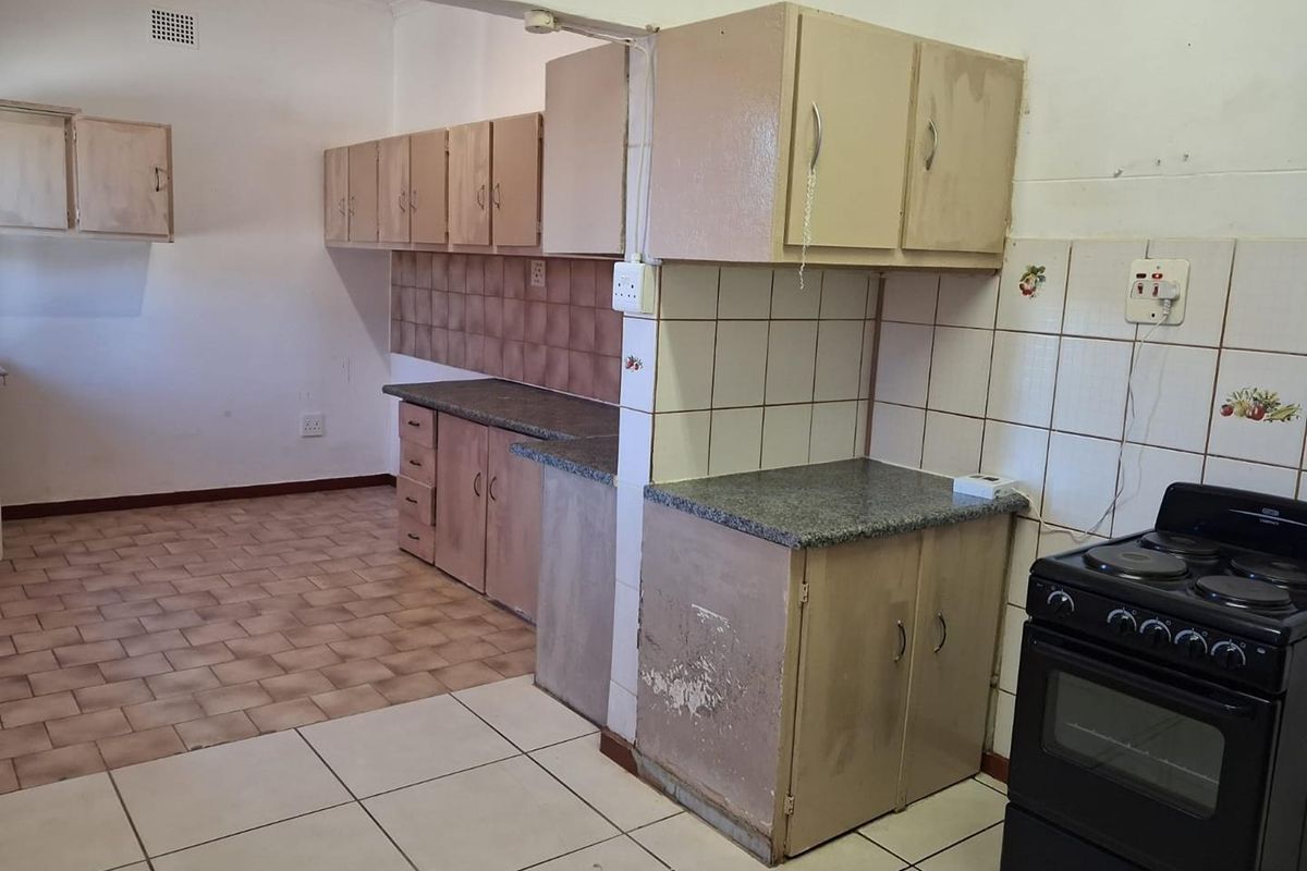 A dated kitchen featuring original cabinetry, tiled splashbacks, and tiled flooring, offering a functional layout ready for modernization and renovation.