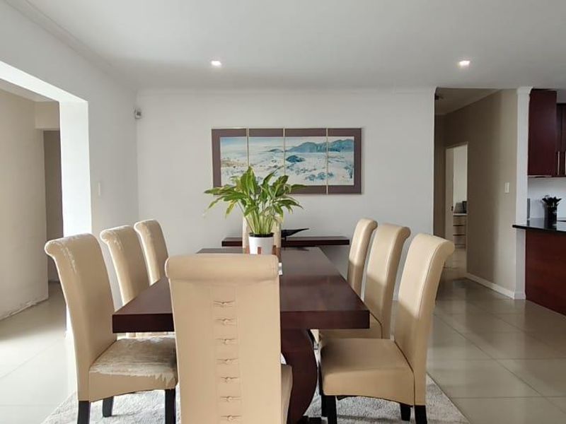 Spacious open-plan living and dining area featuring tiled floors, recessed lighting, and a modern kitchen with dark wood cabinetry and granite countertops.