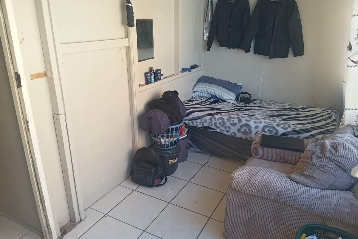 A compact bedroom featuring tiled flooring and a built-in wall niche, currently showing signs of wear and requiring cosmetic updates.