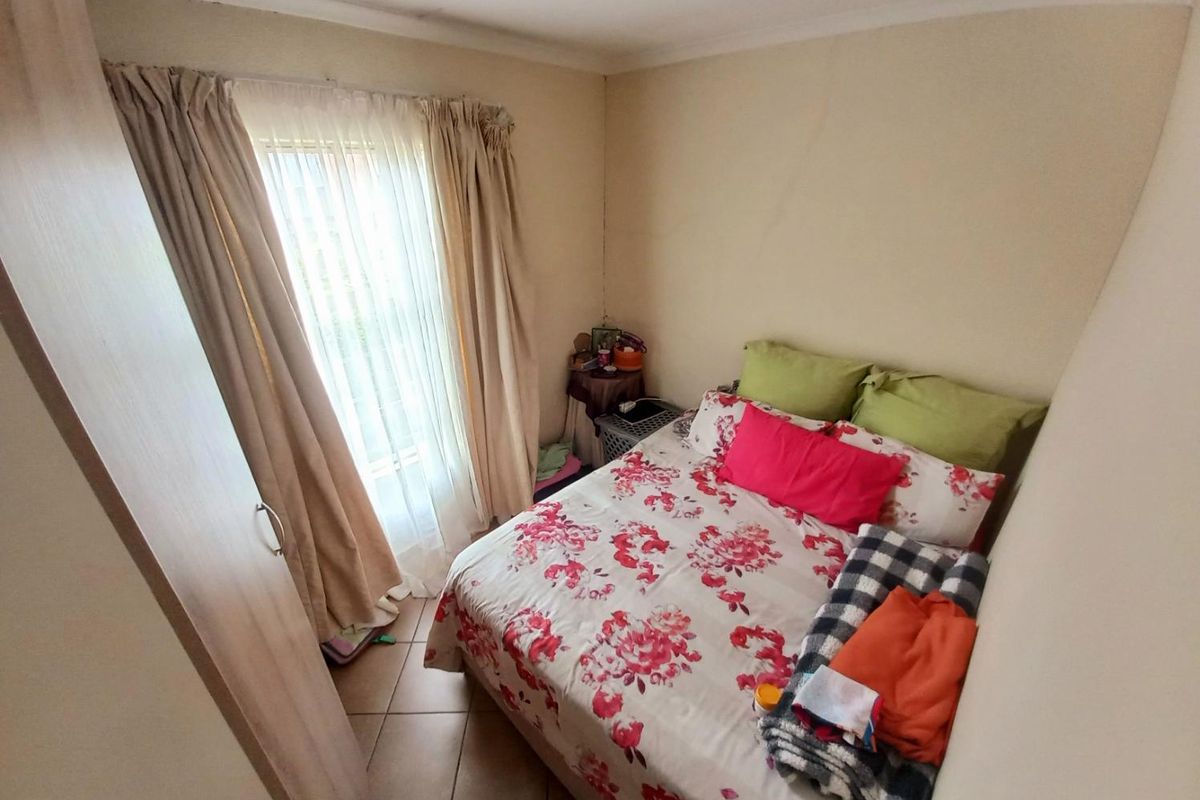 A compact bedroom featuring tiled flooring, built-in cabinetry, and a window with curtain treatments.