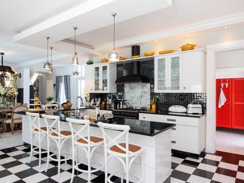 Spacious open-plan kitchen featuring a central island with granite countertops, modern cabinetry, and a striking black and white checkered floor.