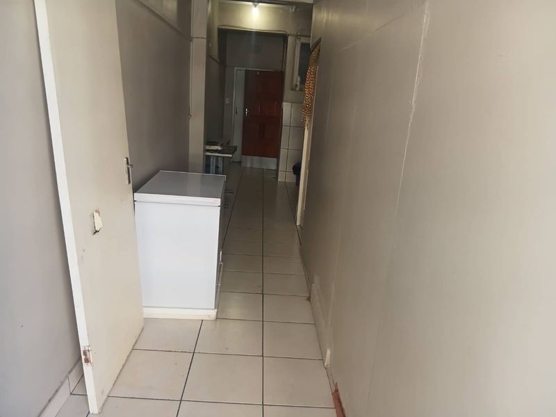 A functional hallway featuring tiled flooring and access to multiple rooms, currently in need of minor cosmetic repairs and maintenance.