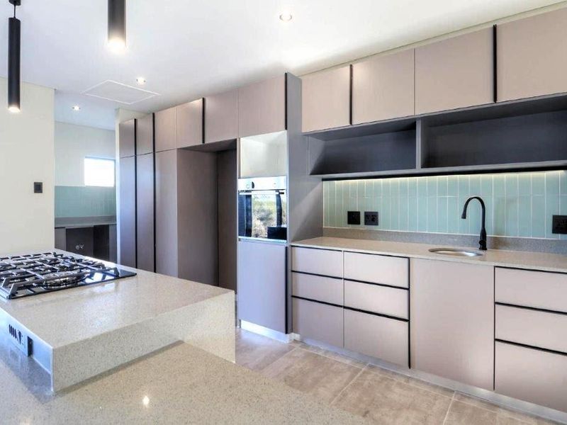 Modern kitchen featuring sleek cabinetry, stone countertops, a gas hob on the central island, and a stylish subway tile backsplash.