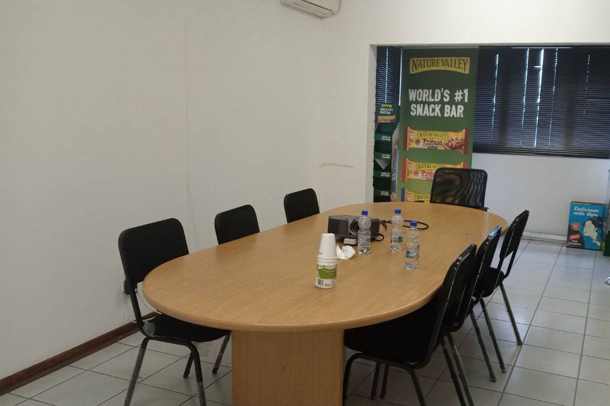 A functional office space featuring tiled flooring, a wall-mounted air conditioning unit, and venetian blinds, suitable for a professional meeting or workspace environment.
