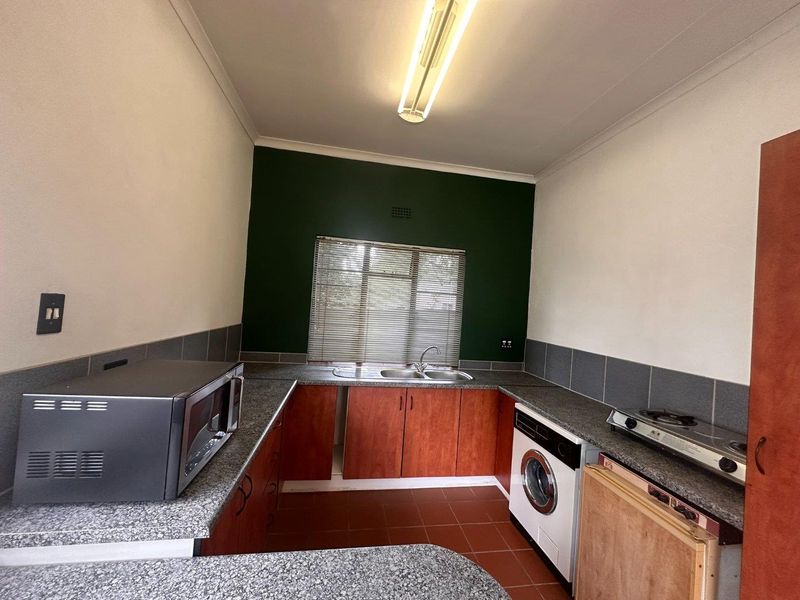 Functional kitchen featuring laminate cabinetry, granite-look countertops, double bowl sink, and tiled splashback, with space for under-counter appliances.