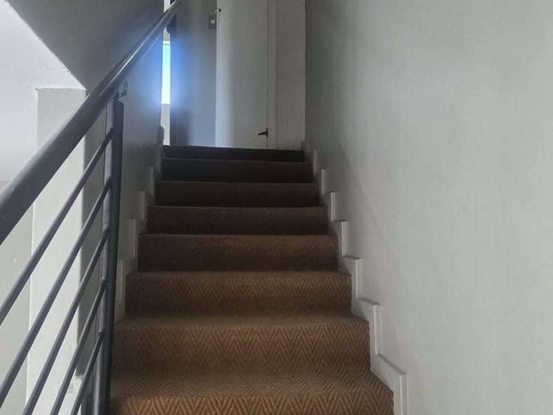A staircase with a metal handrail and carpeted steps leading to an upper level landing.