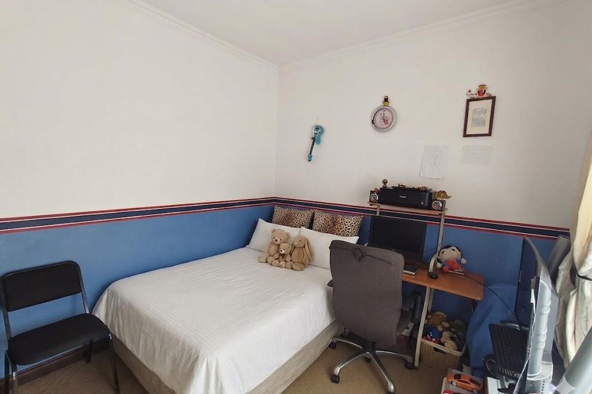 A functional bedroom featuring carpeted flooring and decorative wall trim, providing a comfortable space for rest or study.