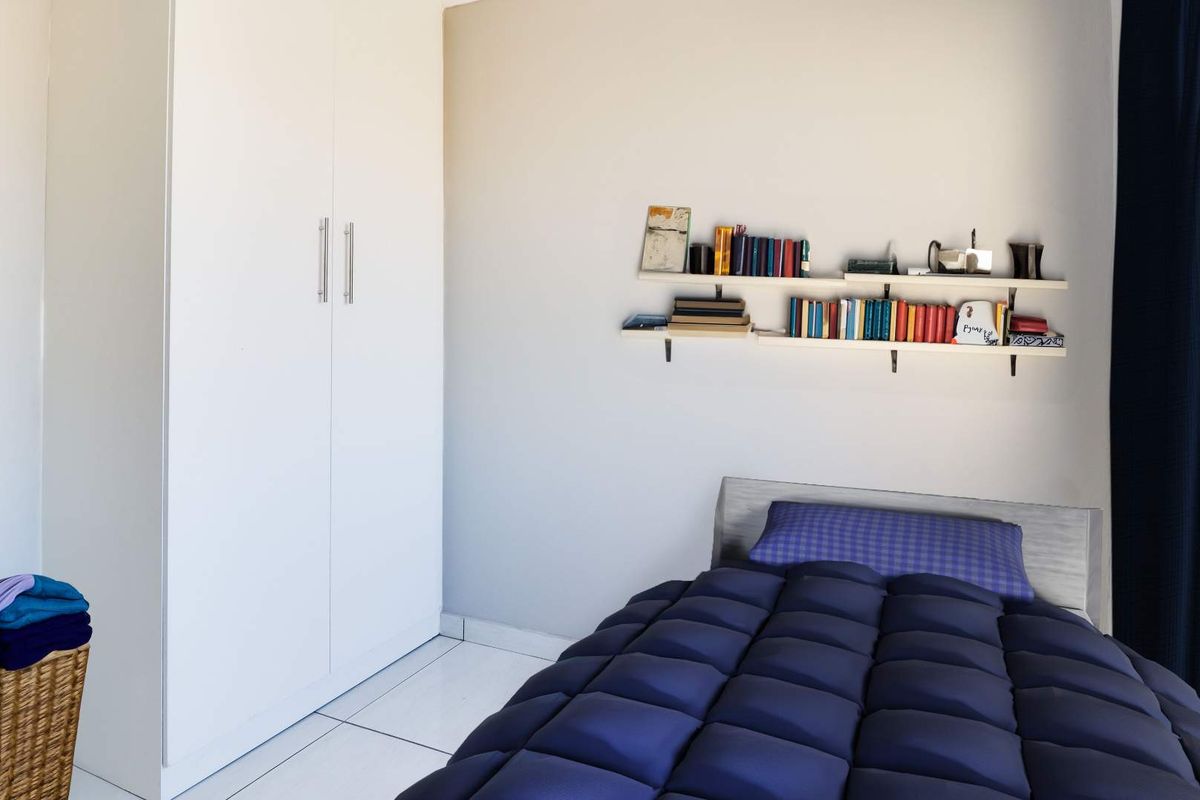 A clean bedroom featuring white built-in wardrobes and neutral tiled flooring, providing a simple and functional living space.