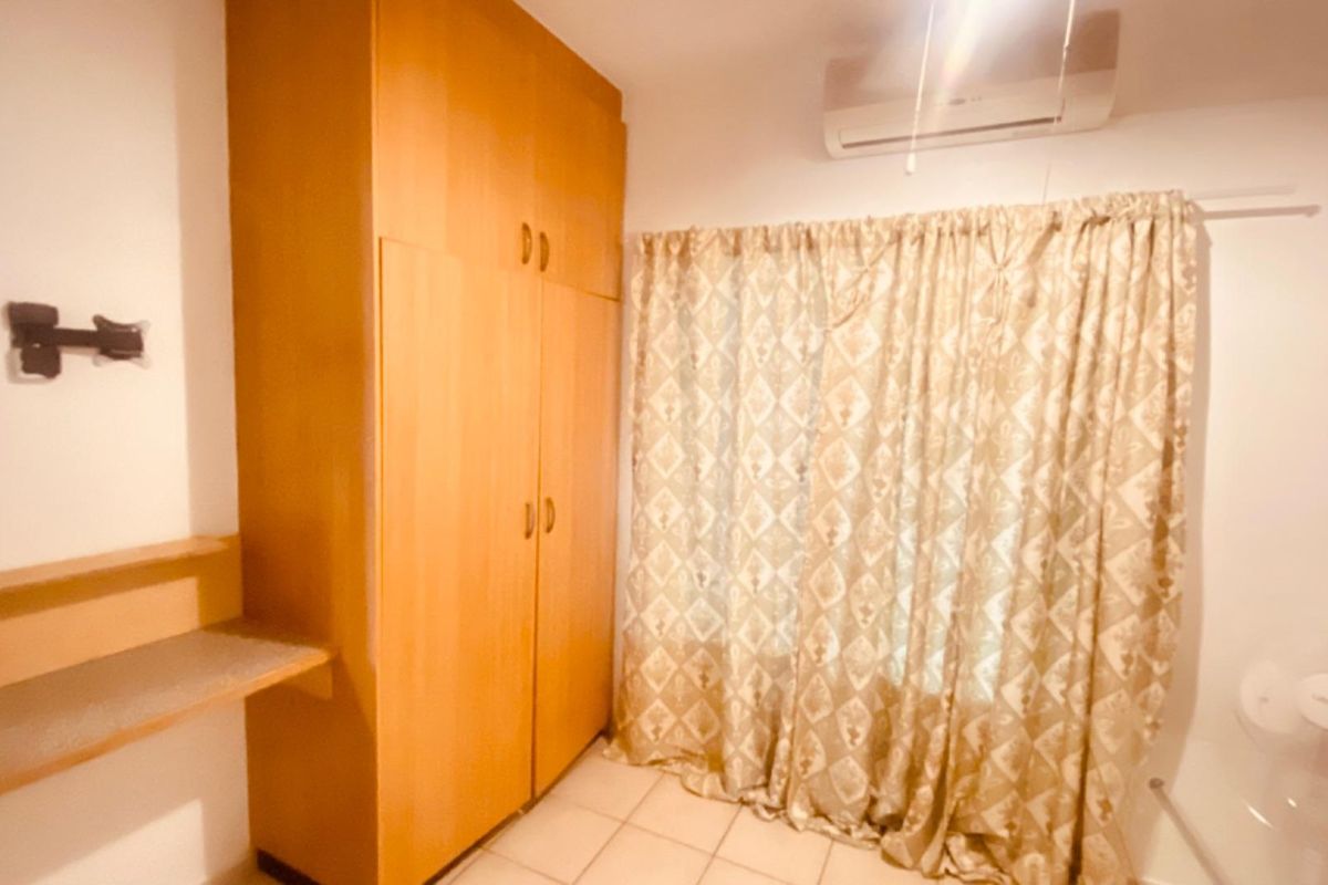 A bedroom featuring built-in wooden cabinetry, tiled flooring, and a wall-mounted air conditioning unit.