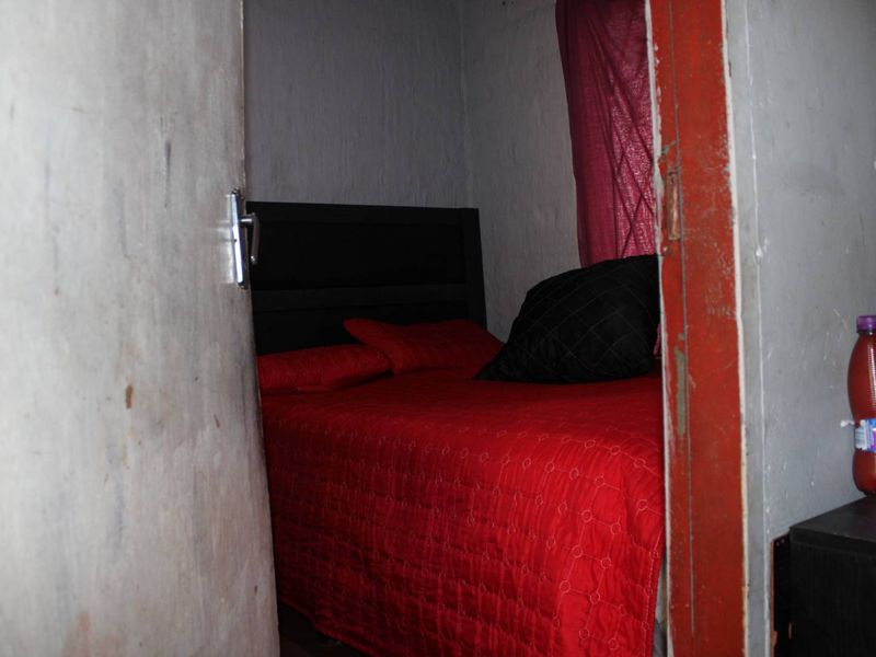 A small bedroom interior showing signs of wear on the door frame and wall finishes, requiring cosmetic updates.