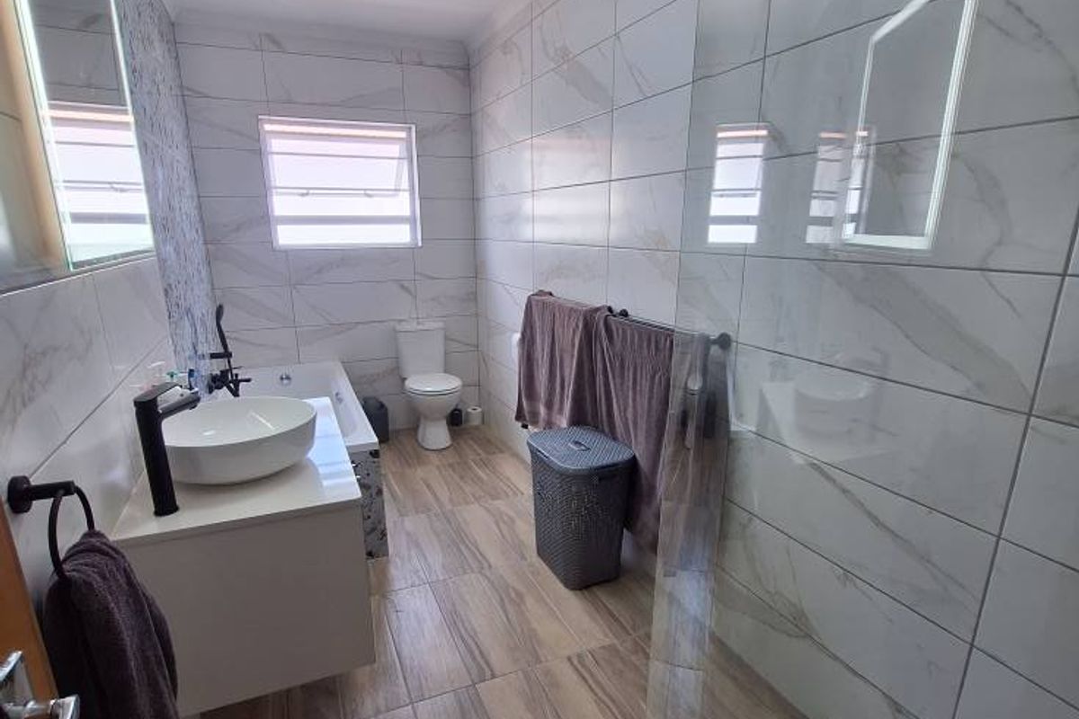 Modern bathroom featuring a glass-enclosed shower, a contemporary vessel sink vanity, a bathtub, and floor-to-ceiling marble-style wall tiling.