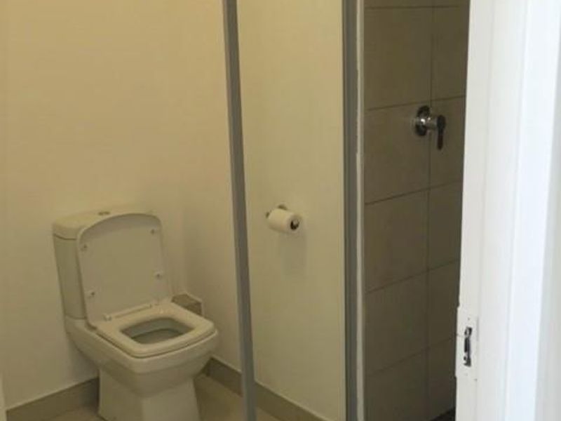 A functional bathroom featuring a toilet and a walk-in shower with a glass screen and tiled finishes.