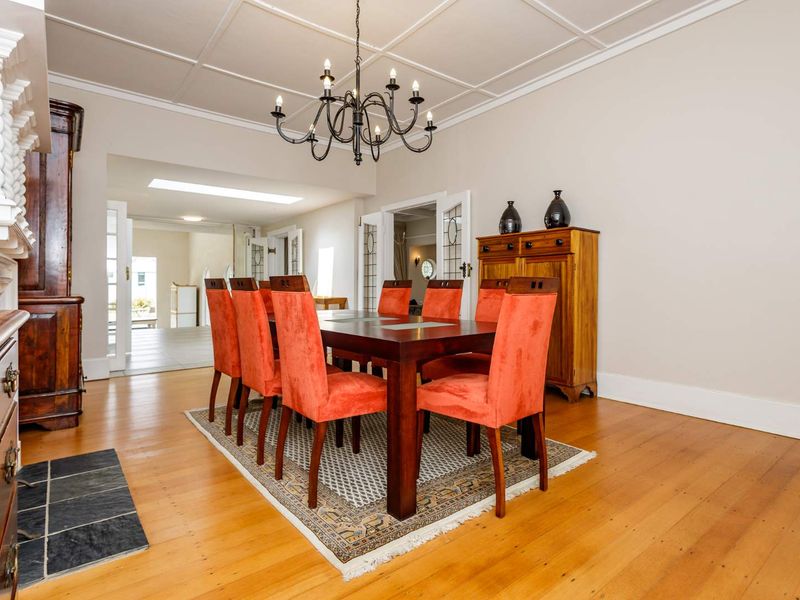 Spacious dining room featuring polished hardwood flooring, a classic coffered ceiling, and elegant french doors leading to adjacent living areas.