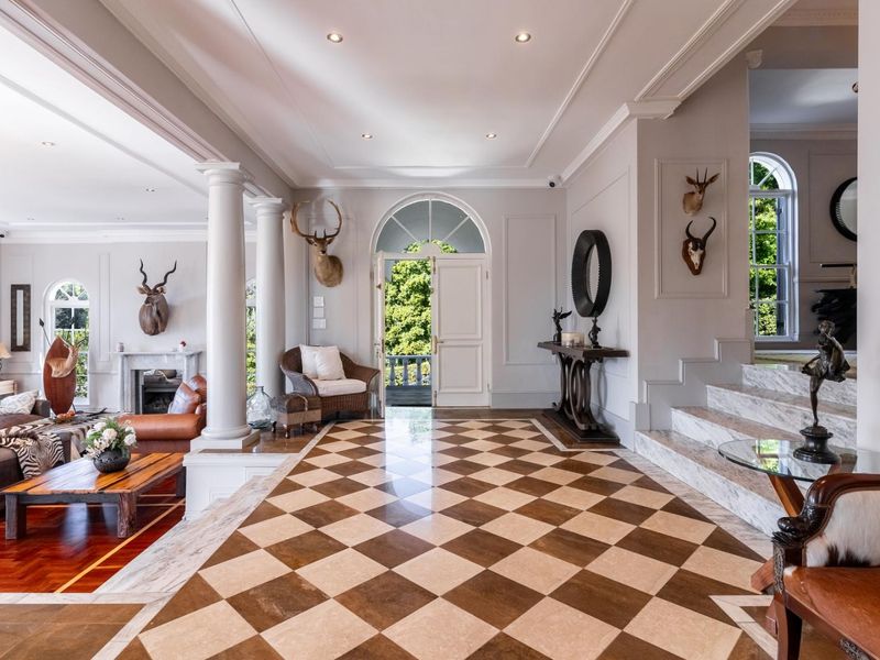 Grand entrance hall featuring elegant checkered marble flooring, classic columns, and a marble staircase leading to upper levels.