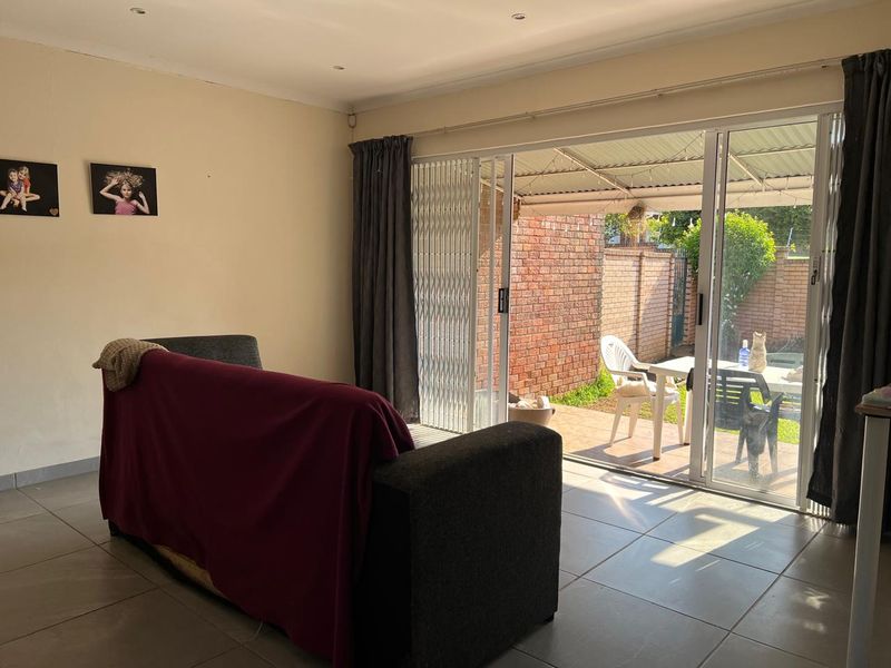 Living room featuring tiled flooring and large sliding glass doors providing direct access to the outdoor patio area.