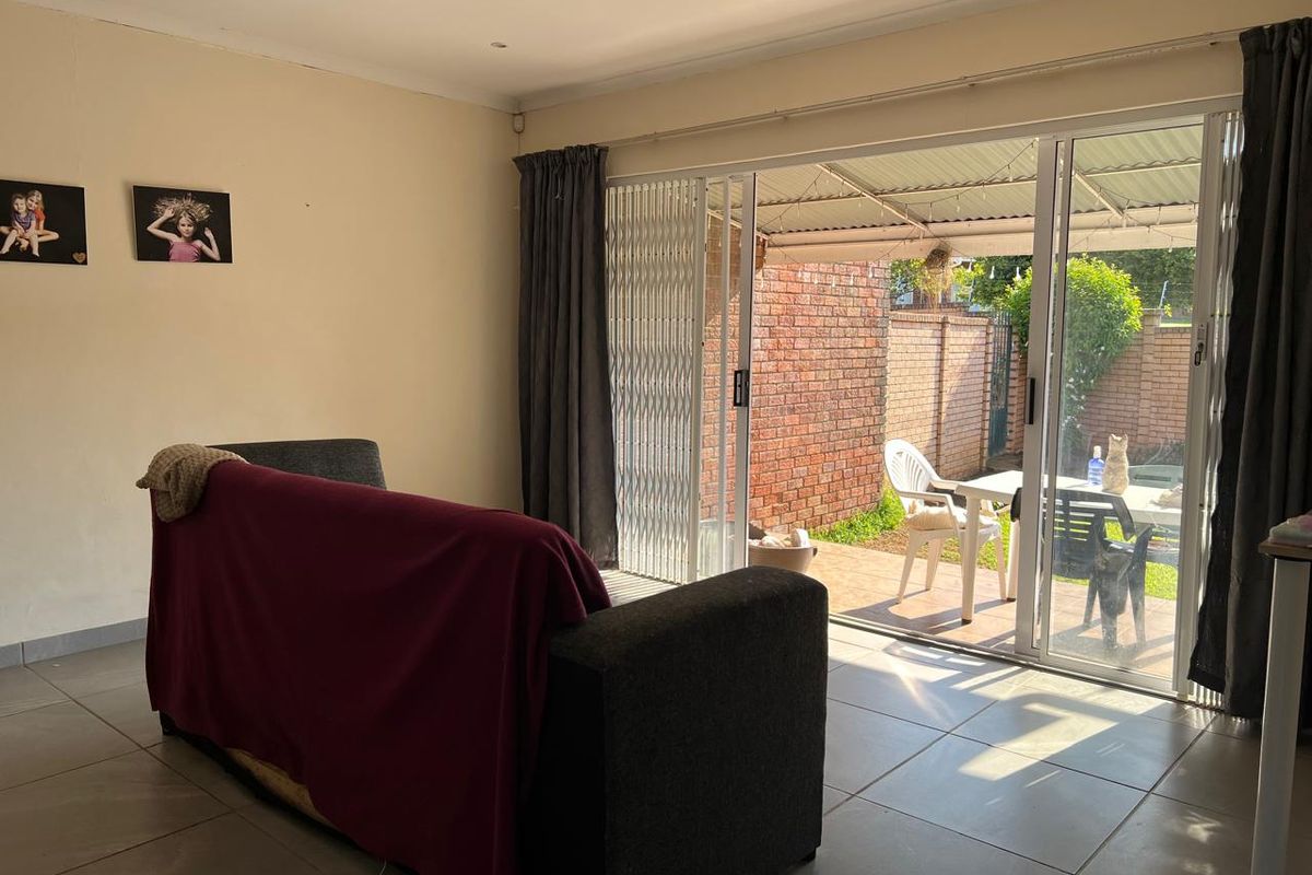 Living room featuring tiled flooring and large sliding glass doors providing direct access to the outdoor patio area.