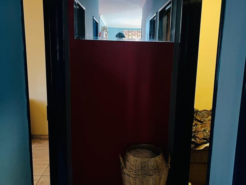 A narrow hallway featuring tiled flooring and dark-painted door frames, providing access to adjacent rooms.
