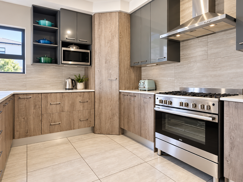 Modern kitchen featuring wood-grain and grey cabinetry, stone countertops, stainless steel gas stove, and integrated extractor fan with neutral tiled flooring.