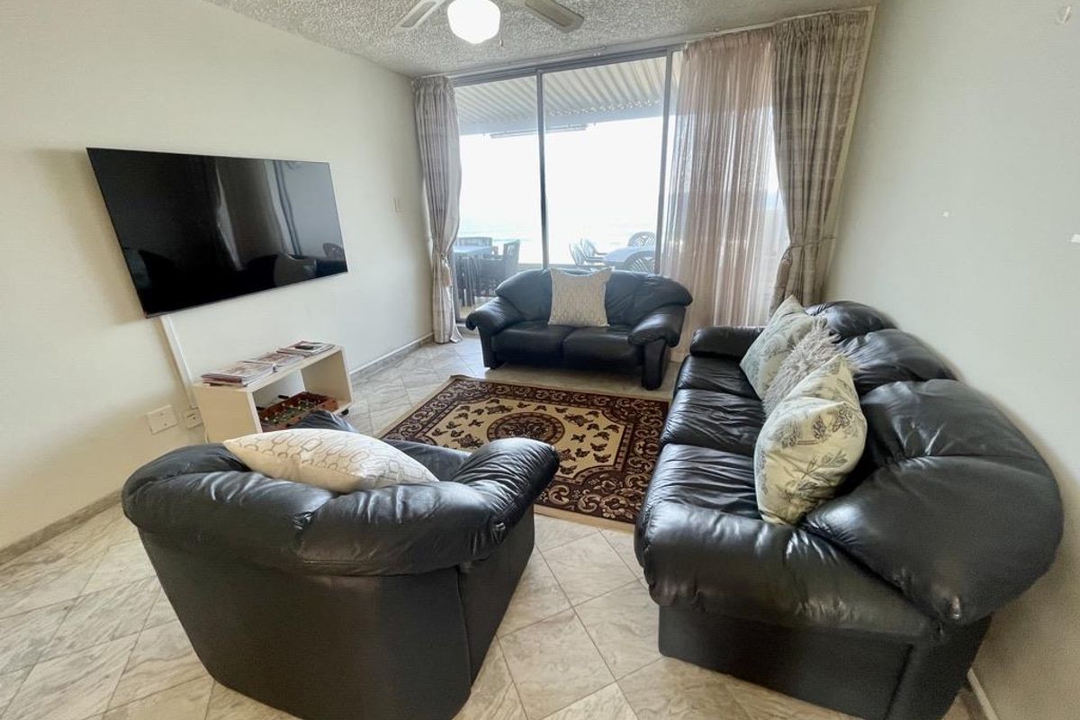 A living room featuring tiled flooring, a ceiling fan, and large sliding glass doors that provide natural light and access to the balcony.