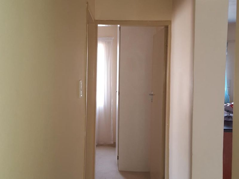 A functional hallway featuring tiled flooring and access to adjacent rooms, providing a clean and neutral transition space within the apartment.