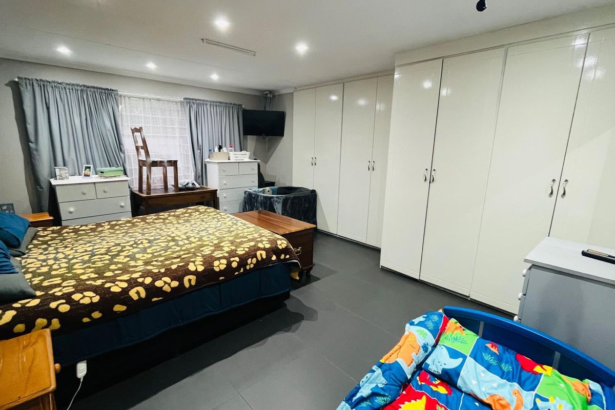 Spacious bedroom featuring extensive built-in cabinetry with high-gloss finish, recessed ceiling lighting, and dark tiled flooring.