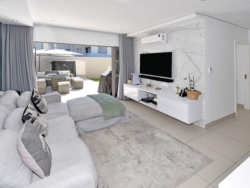Modern living room featuring a marble-look feature wall, split-system air conditioning, and seamless flow to an outdoor patio area through large sliding glass doors.