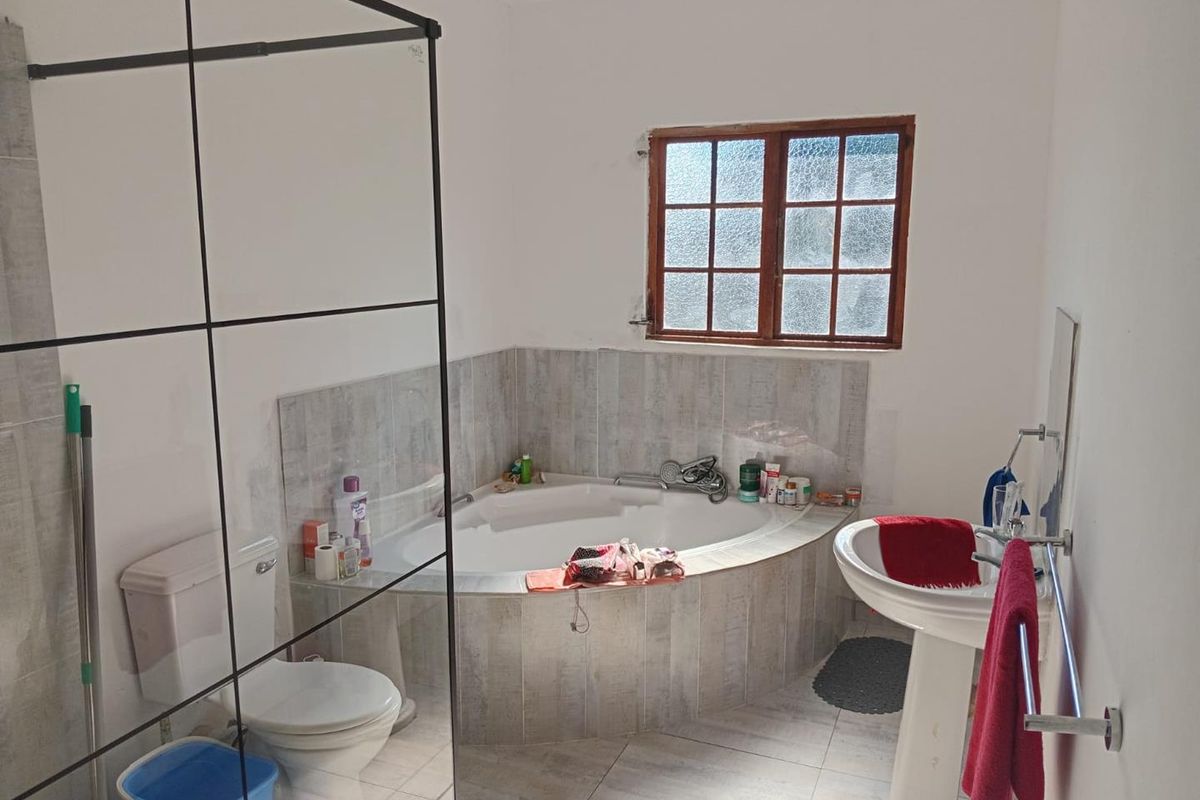 A functional bathroom featuring a corner bathtub, pedestal basin, and a glass-enclosed shower area with neutral tiled finishes.