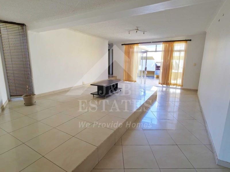Spacious living area featuring a raised platform, tiled flooring, and sliding glass doors leading to an outdoor space.