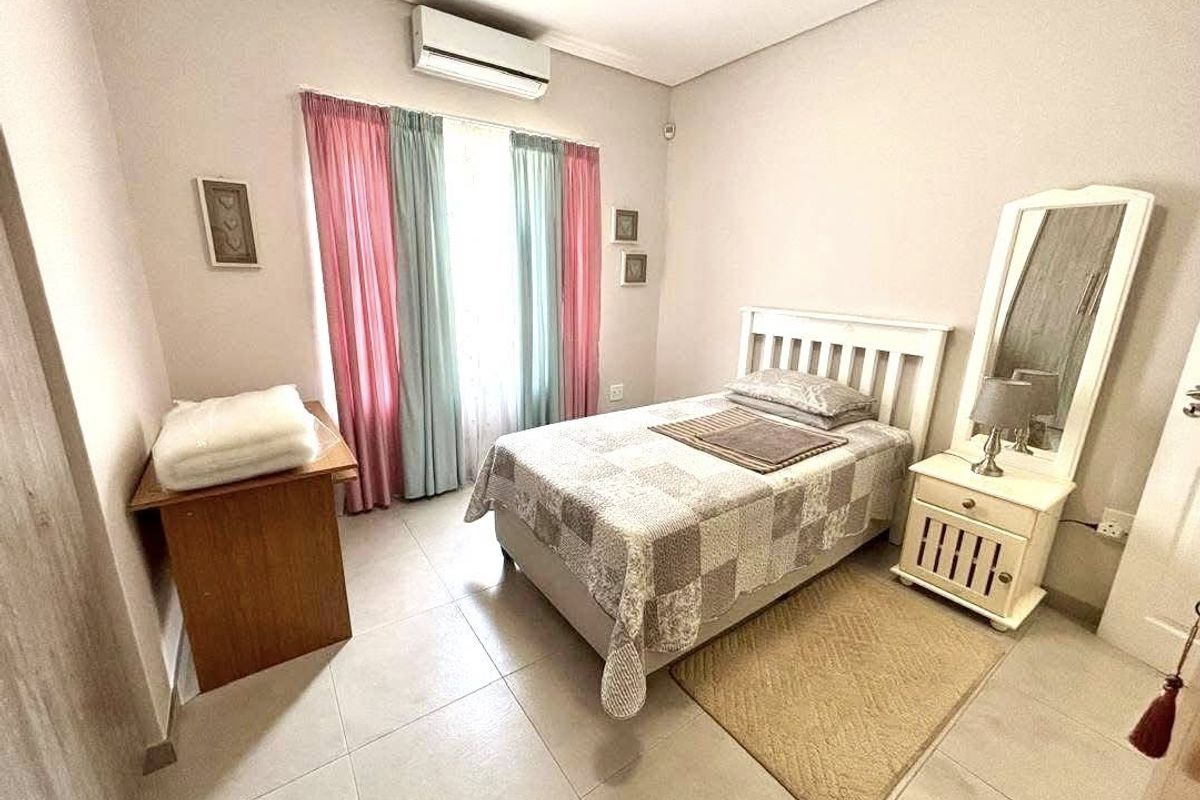 A functional bedroom featuring tiled flooring and a wall-mounted split-system air conditioning unit.