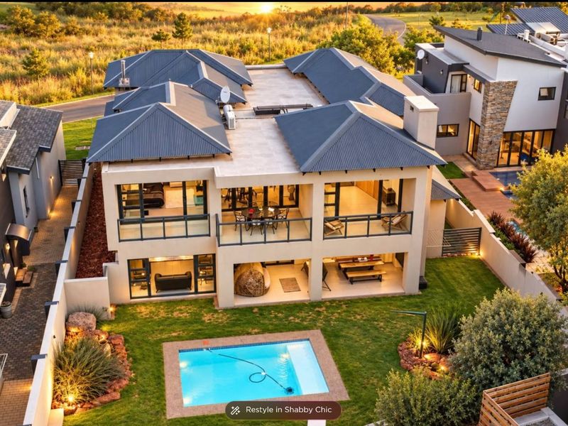 Aerial view of a modern double-story residence featuring a swimming pool, landscaped garden, covered patios, and balconies with contemporary architectural design.