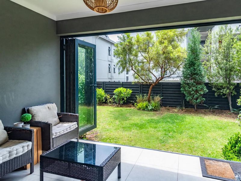 A modern covered patio featuring large folding glass doors that open onto a private garden, providing seamless indoor-outdoor flow.