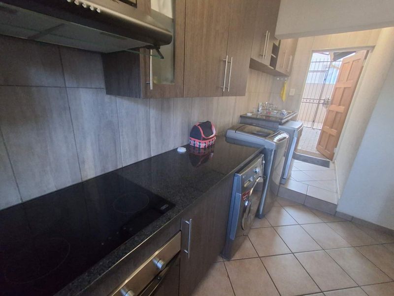 A functional kitchen featuring dark wood cabinetry, granite countertops, integrated appliances, and tiled flooring, with direct access to an outdoor area.