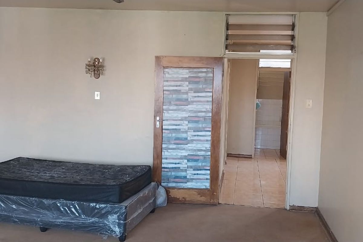 A bedroom featuring carpeted flooring, a single interior door, and access to an adjoining tiled hallway.