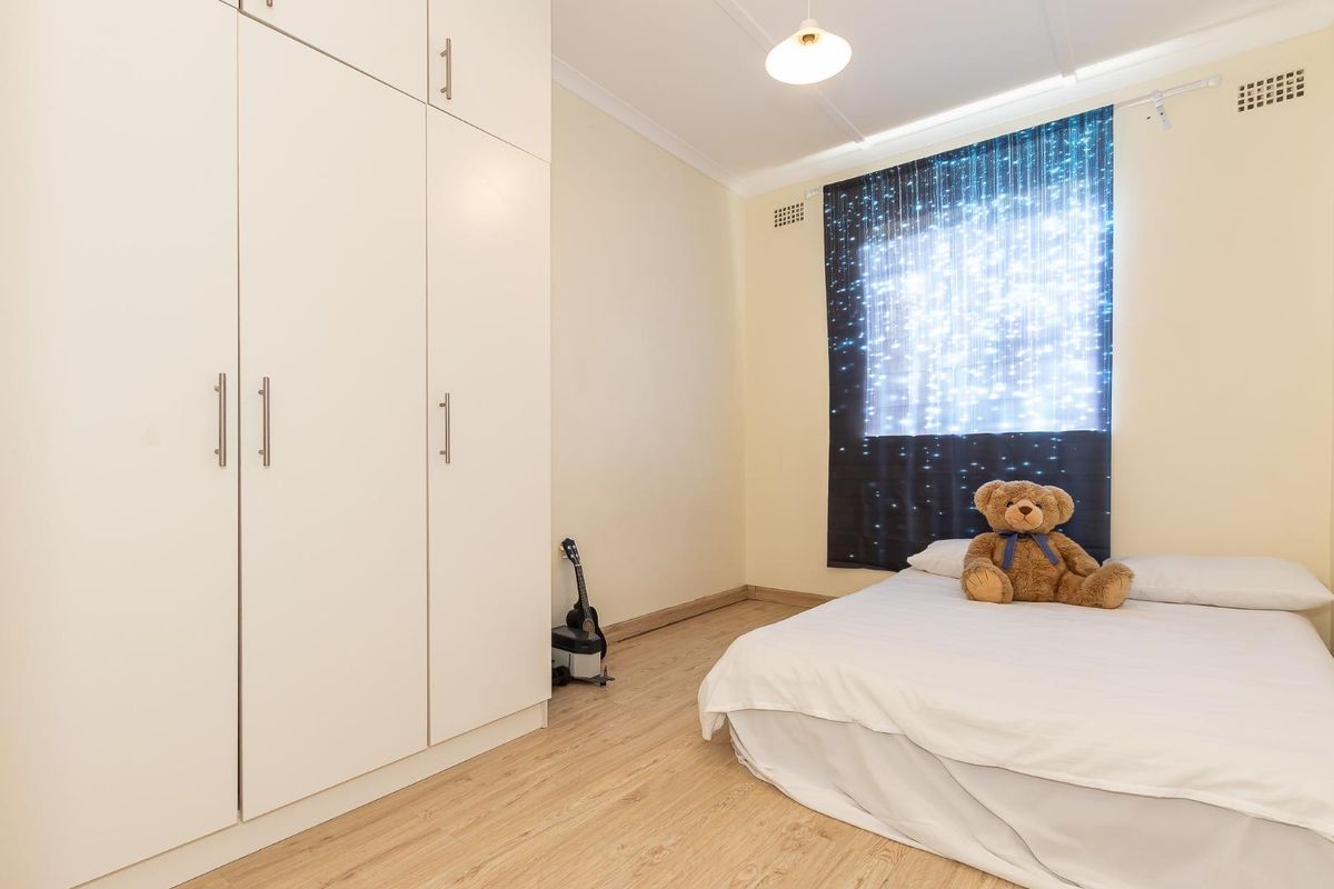 A bedroom featuring light wood-look flooring and built-in floor-to-ceiling white cabinetry providing ample storage space.