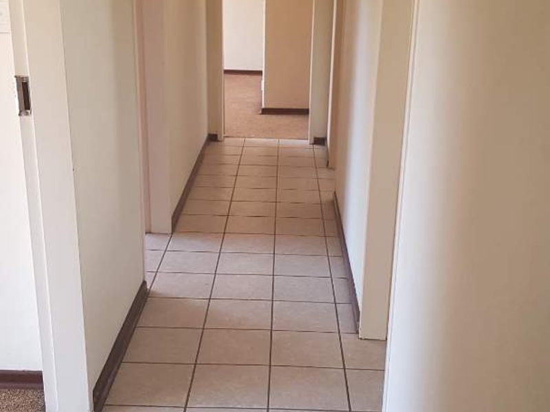 A functional hallway featuring neutral ceramic floor tiles and connecting multiple rooms throughout the home.