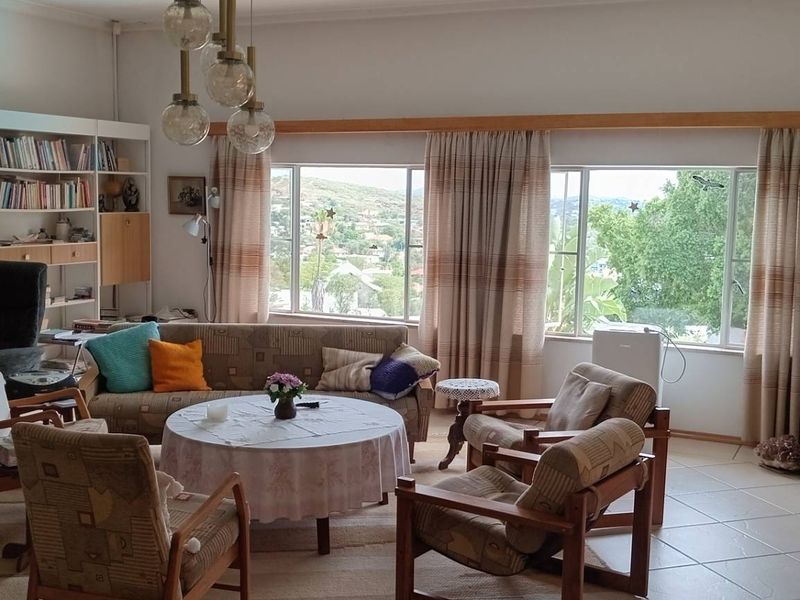 Spacious living room featuring tiled flooring, large windows with scenic views, and a built-in shelving unit, offering a bright and comfortable living space.