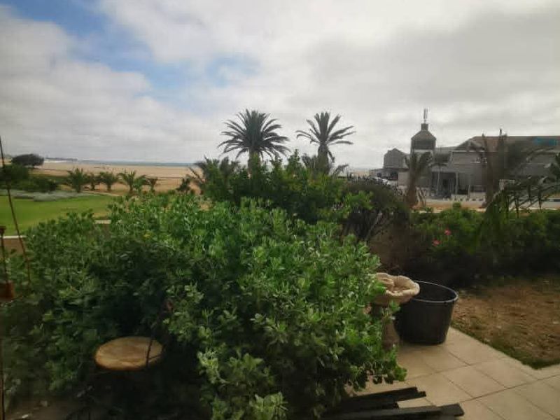 A covered patio area featuring tiled flooring with an open view towards the garden and coastal landscape.