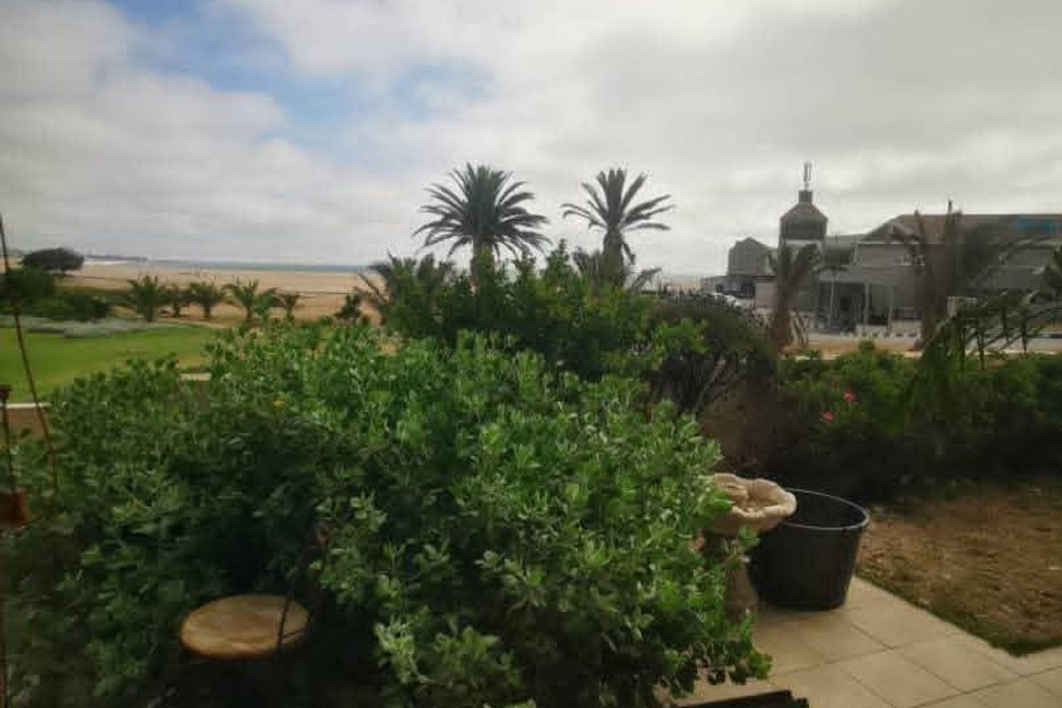 A covered patio area featuring tiled flooring with an open view towards the garden and coastal landscape.