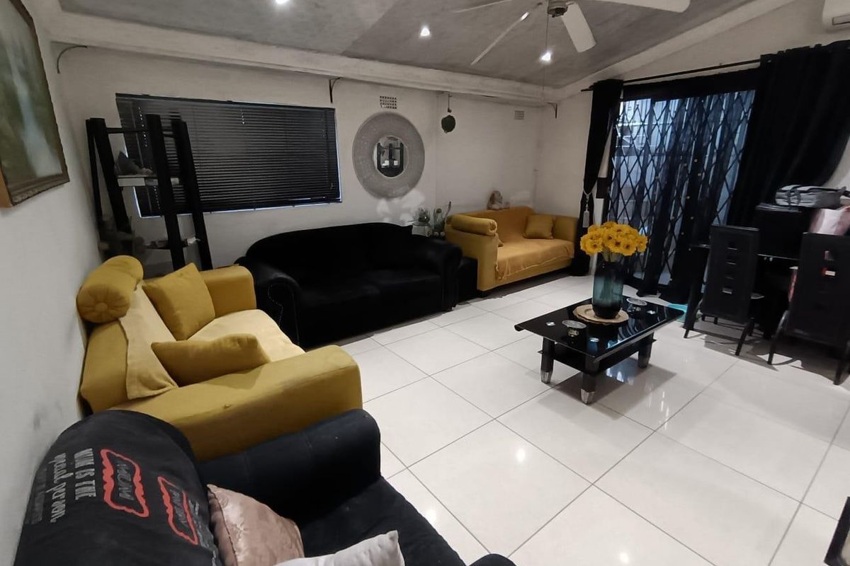 A living room featuring large format floor tiles, recessed ceiling lighting, a central ceiling fan, and sliding glass doors leading to an outdoor area.