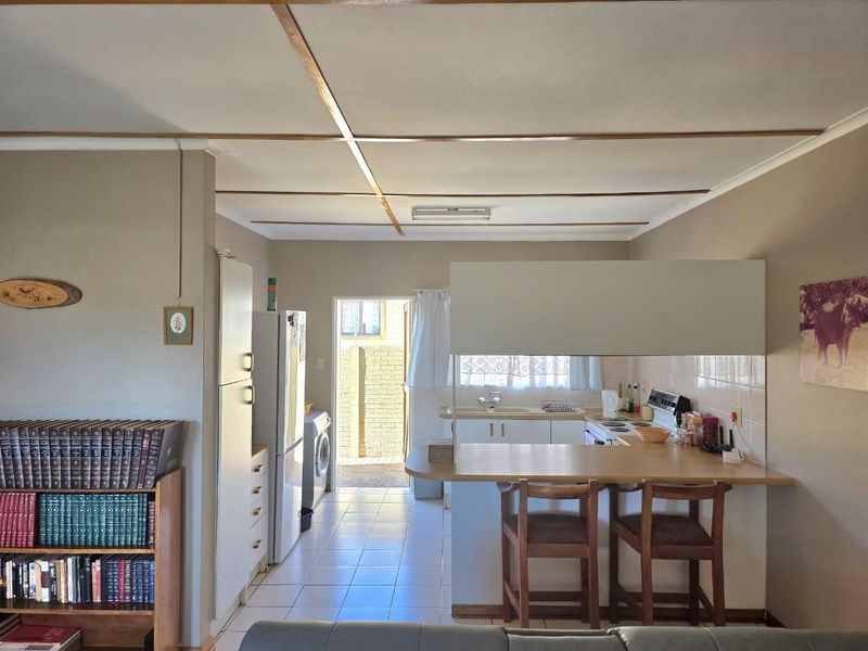Open-plan kitchen and living area featuring a breakfast bar, tiled flooring, and functional built-in cabinetry with direct access to an outdoor area.