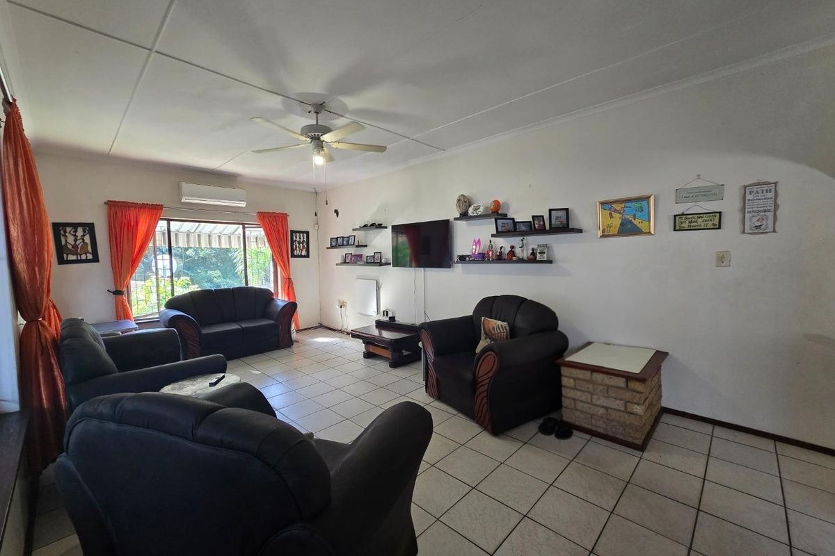 Spacious living room featuring tiled flooring, a ceiling fan, and a split-system air conditioner, providing a comfortable and functional living space.