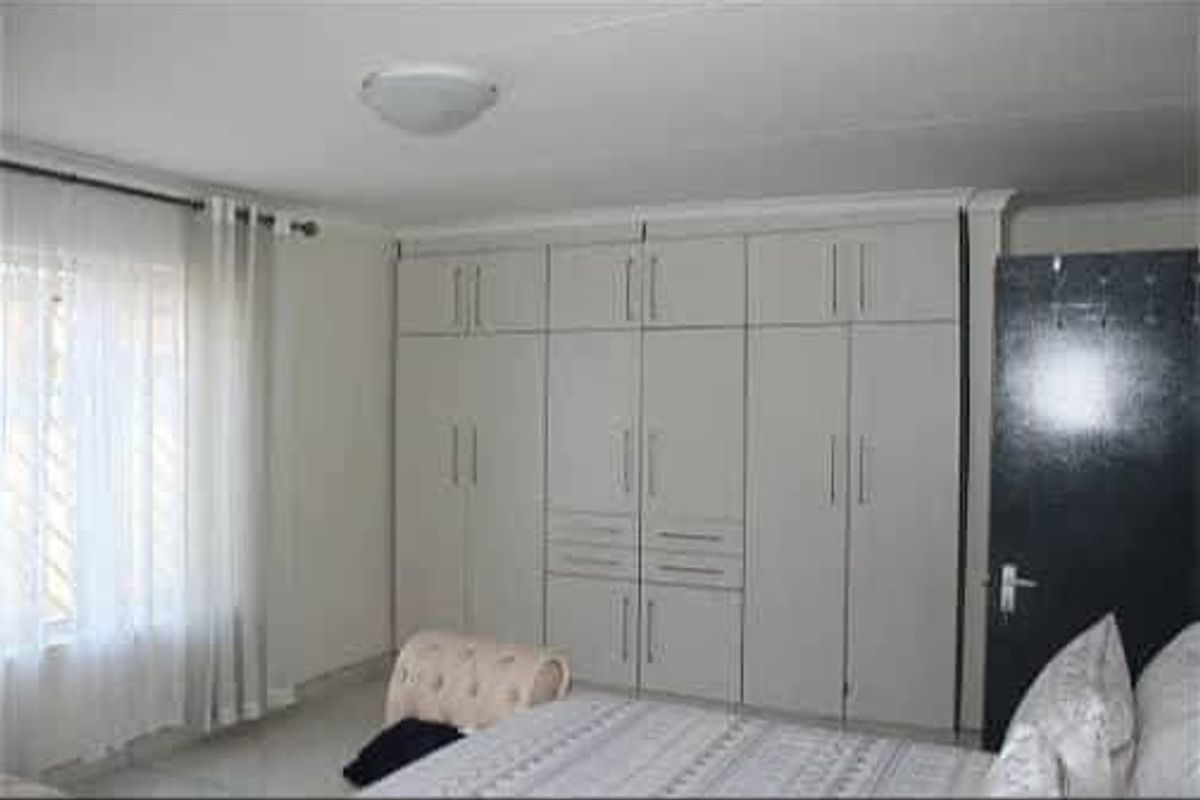 A well-maintained bedroom featuring extensive floor-to-ceiling built-in cabinetry providing ample storage space and neutral finishes.