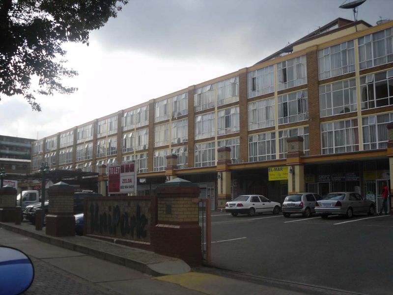 Front exterior view of a multi-story commercial building featuring brick facade, large windows, and ground-level retail storefronts with dedicated parking.
