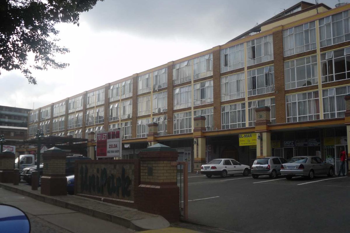 Front exterior view of a multi-story commercial building featuring brick facade, large windows, and ground-level retail storefronts with dedicated parking.