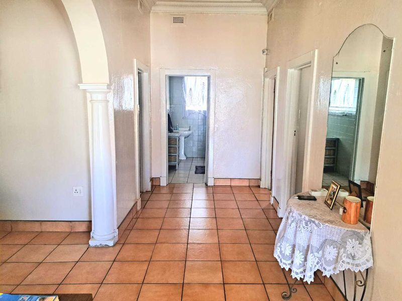 A spacious hallway featuring tiled flooring, a decorative archway with a column, and access to multiple rooms, including a bathroom.