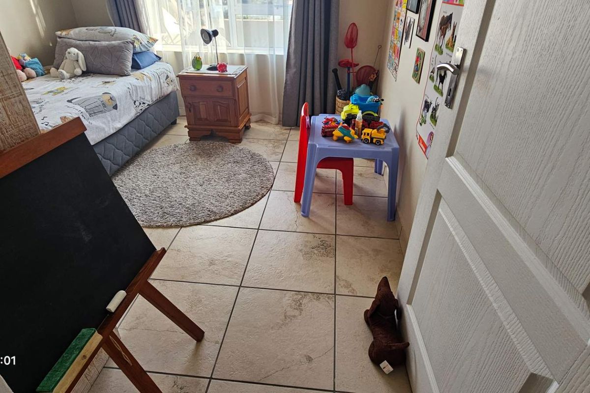 A functional bedroom featuring tiled flooring and natural light, currently utilized as a child's bedroom.