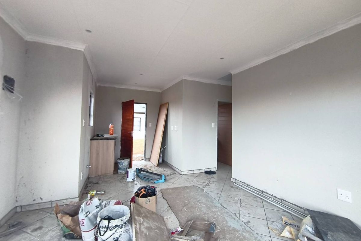 An interior view of a room currently under construction, featuring tiled flooring and neutral wall finishes, awaiting final completion and detailing.