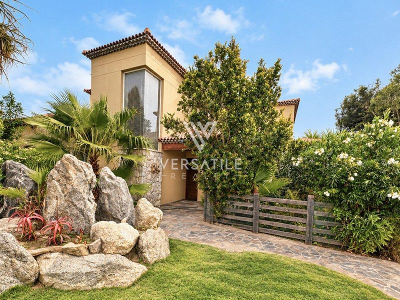 Front exterior view of a townhouse featuring stone cladding, a tiled roof, and a well-maintained landscaped garden with a paved walkway.
